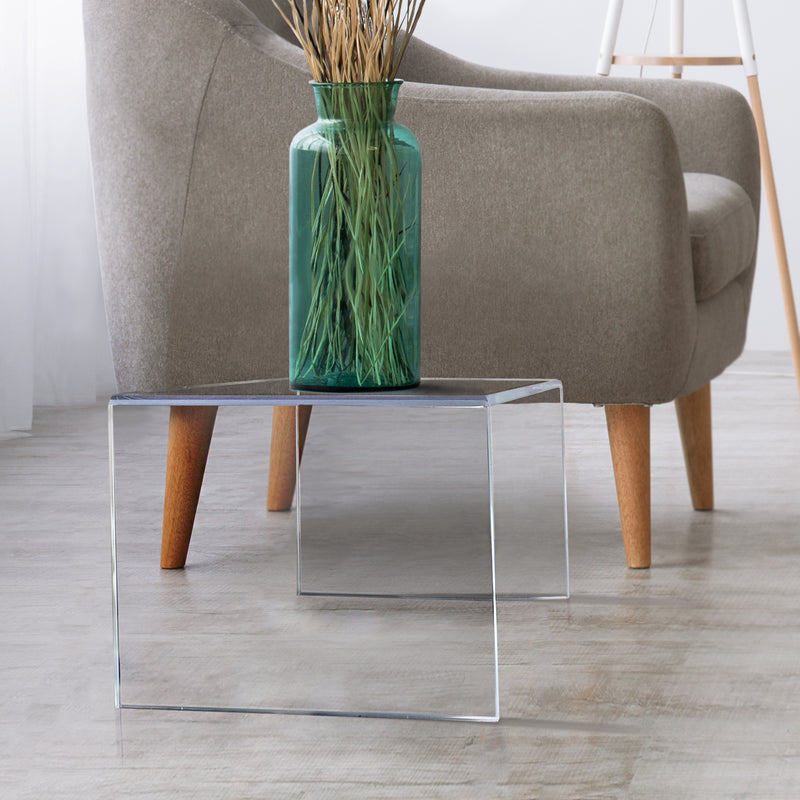 clear acrylic side table next to chair with vase on top