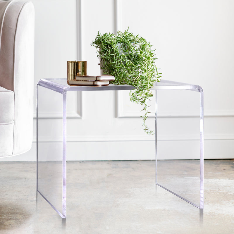 clear acrylic side table with plant and books on top